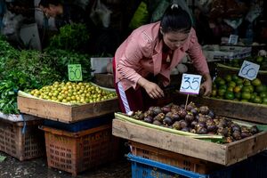 Young woman with a Phra Kruang taking Mangosteen in a fruit store