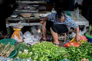 Older woman scouting around in Maeklong Railway Market