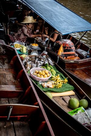 Vendor on a boat selling fruits to tourists on another boat