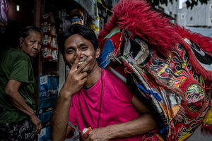 獅子舞の面を担いでピースサインをする男