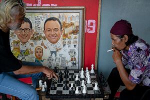 Men playing chess beside a paiting