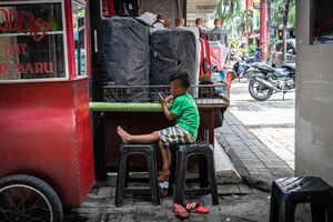 Boy watching the phone screen in Pasar Baru