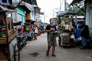 皿を片手に路地を歩く女