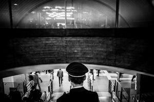 エスカレータに乗った制服を来た渋谷駅員