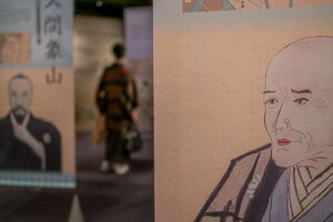 Woman in a kimono seen between the portraits