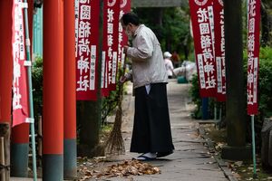 花園稲荷神社の参道を箒で掃く禰宜