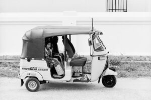 Woman sitting on rear seat of three wheeler