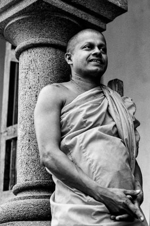 Buddhist monk leaning against pillar