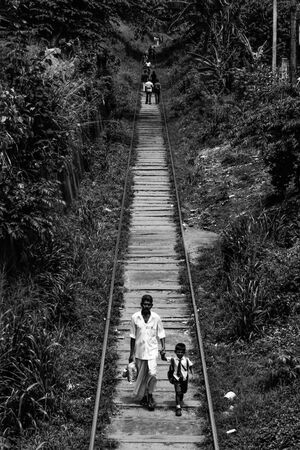 Father and son walking on railway track together