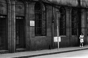 Woman standing alone in front of stone-built building