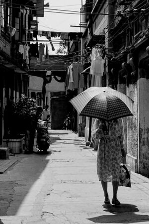 日傘を差して路地を歩く女性