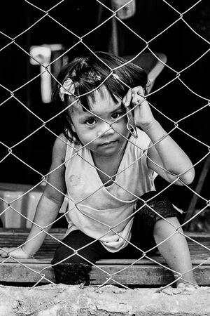 Girl sitting on the other side of wire netting