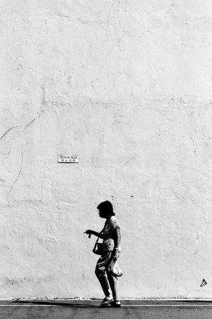Woman walking in front of tall wall