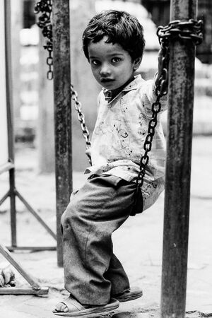 Boy sitting on chain alone