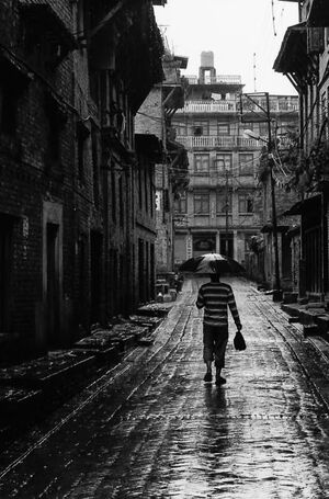 雨の中を傘を差して歩く男