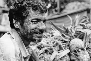 Man smiling beside pineapples
