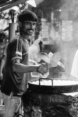 Man working in food stall with round pan