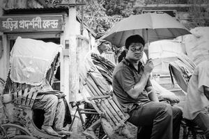 Passenger on cycyle rickshaw putting umbrella up