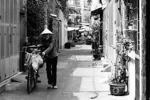 路地を自転車を押して歩く行商人