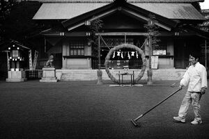 Shinto priest raking graveled precinct