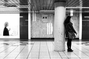柱の横に立って電話する若い女性