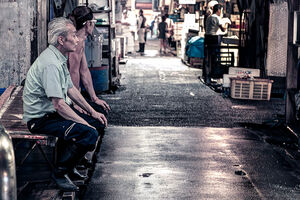 市場の通路に腰掛ける二人の男