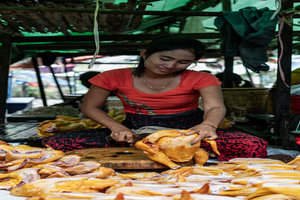 Woman cutting poultry meat in crossed-leg position