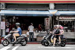 Motorbikes waiting at traffic light in front of shop