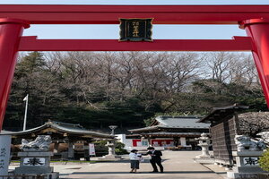 武州柿生琴平神社の鳥居とお宮参りに来た若夫婦