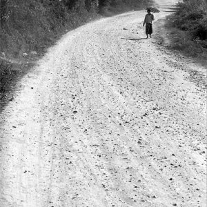 Woman walking dirt road with sunshade