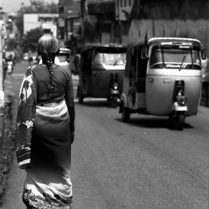 Three wheelers passing by woman with saree