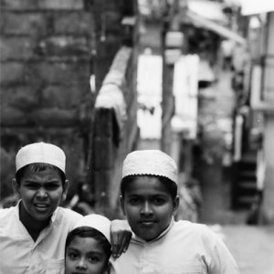 Three boys wearing white Taqiyah