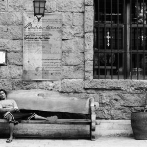 Man taking nap on bench placed in front of souvenir shop