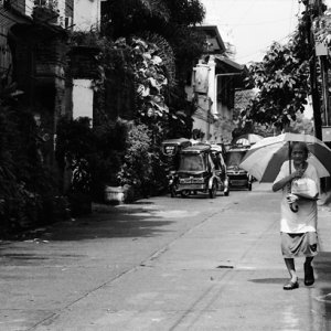 強い日差しの中を日傘を差して歩く老婆