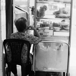 Older woman sitting beside glass box