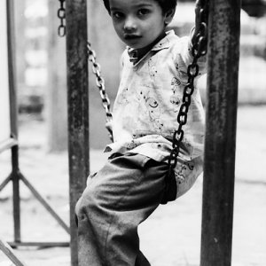 Boy sitting on chain alone