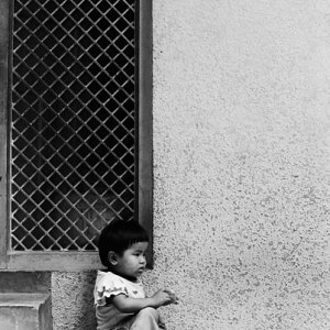 Little kid sitting alone under eaves