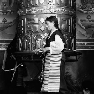 Older woman turing around big prayer wheel