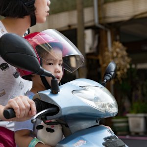 A boy riding a motorcycle with his mother