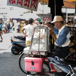 Old man reading newspaper at a corner of the market