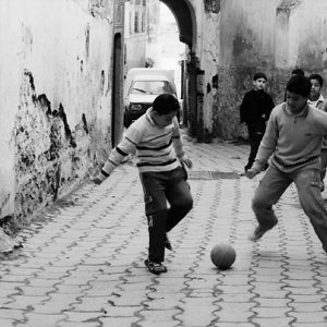 路地でサッカーをする男の子たち