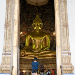 two Buddha statues and a worshiper