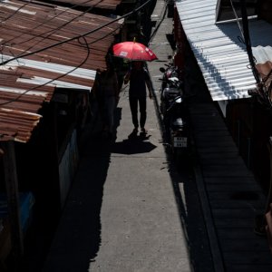 Figure with red umbrella walking between zinc roofs