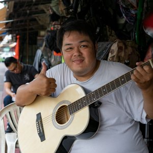 Young man thumbing up while holding guitar