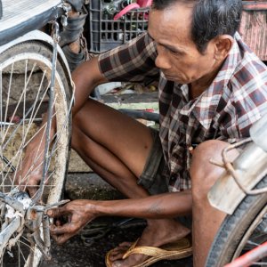 自転車タクシーを修理する男