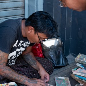 Man repairing an used book by the wayside