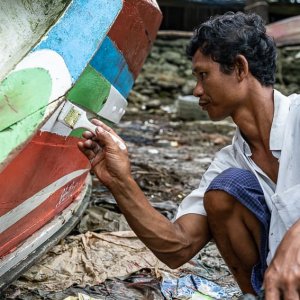 Man recoloring fishing boat
