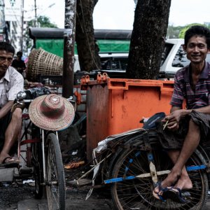Rickshaw men sat on saddle of vehicle