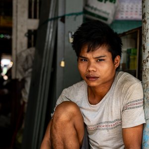 Young man sitting at entrance of market