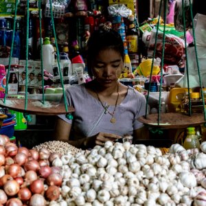 Woman working on the other side of pile of garlic